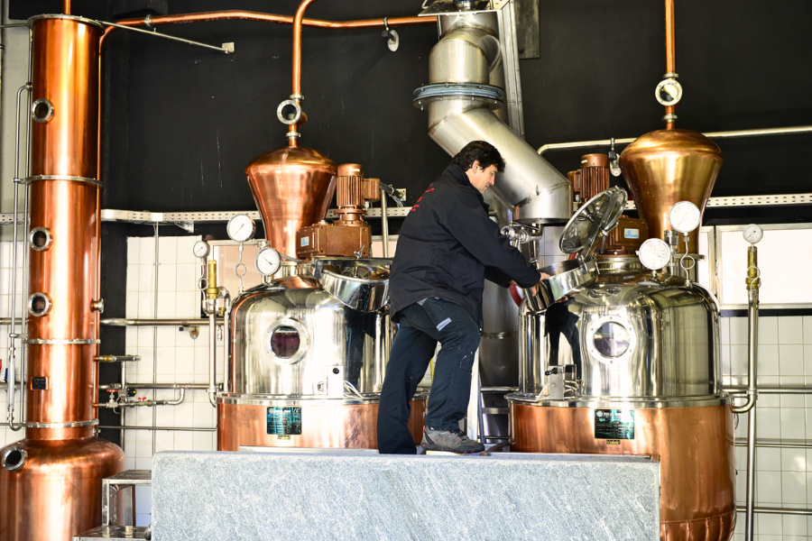 Alambicchi in rame della distilleria, con un operatore al lavoro